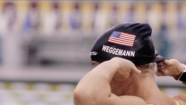 Screen grab of Mallory Weggeman putting on her black team usa swim cap 