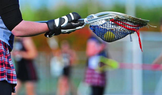 Abstract view from the goal of a girls lacrosse game as the goalie prepares to pass the ball to one of her team mates.