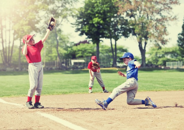 Boy sliding into base during a baseball game with Instagram style filter, focus is on catcher.