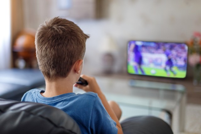 Excited little kid watching soccer match in TV at home