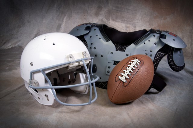 Football helmet and shoulder pads on tan background